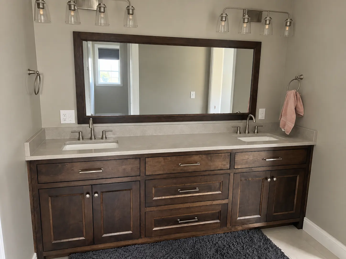 Stained double-sink bathroom vanity with a wide wood-framed mirror