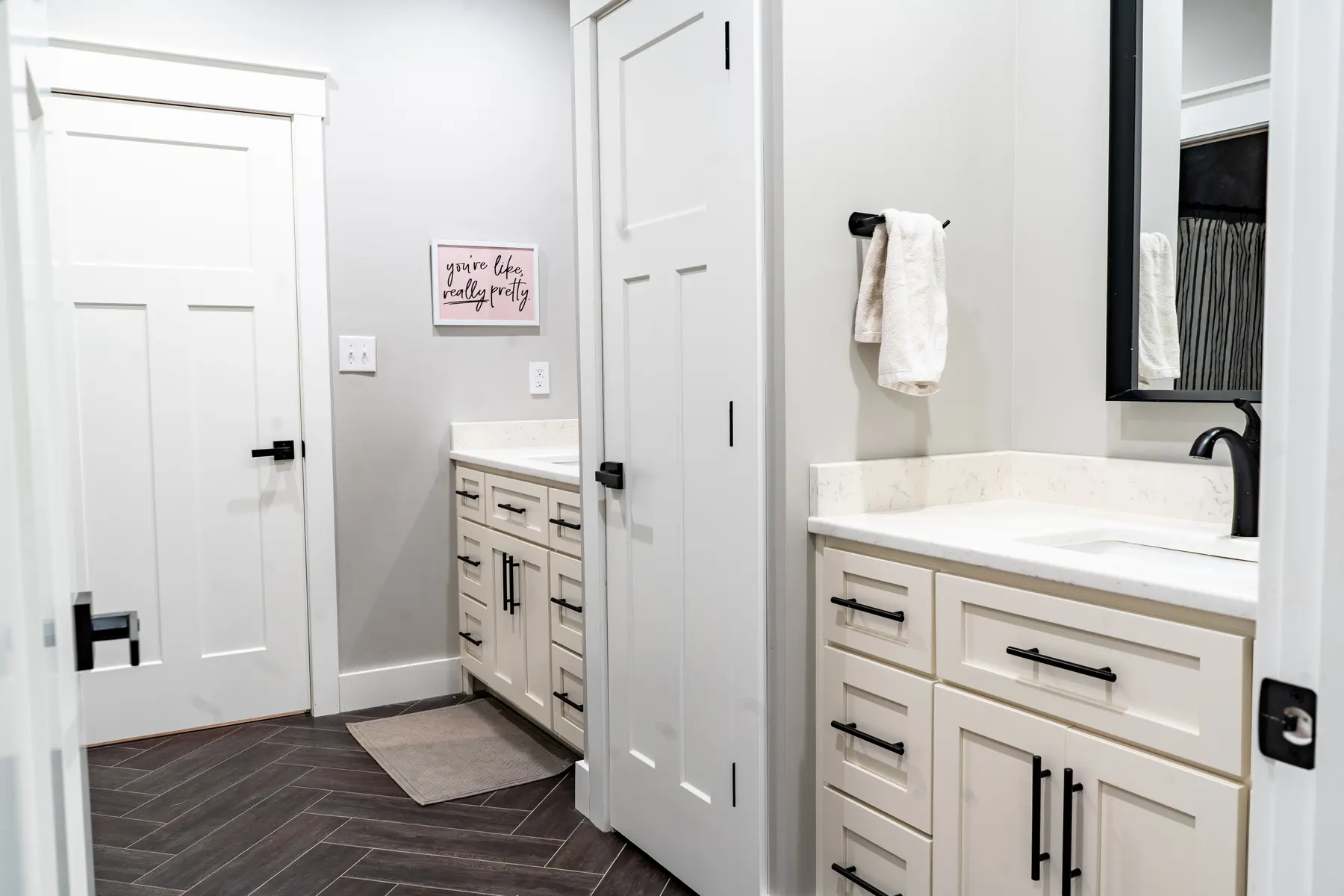 Cream bathroom with two custom vanities and black hardware