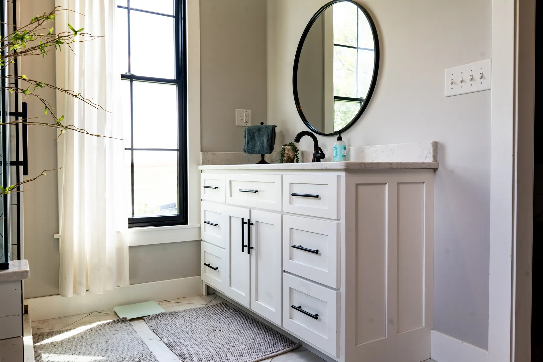 White shaker bathroom vanity beside a black-framed window