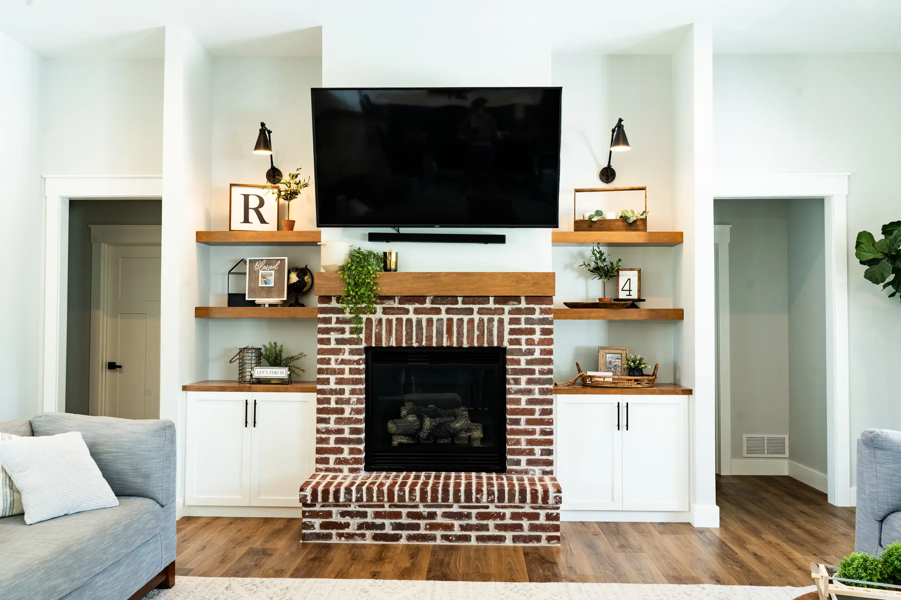White built-in cabinets and wood shelves flanking a brick fireplace