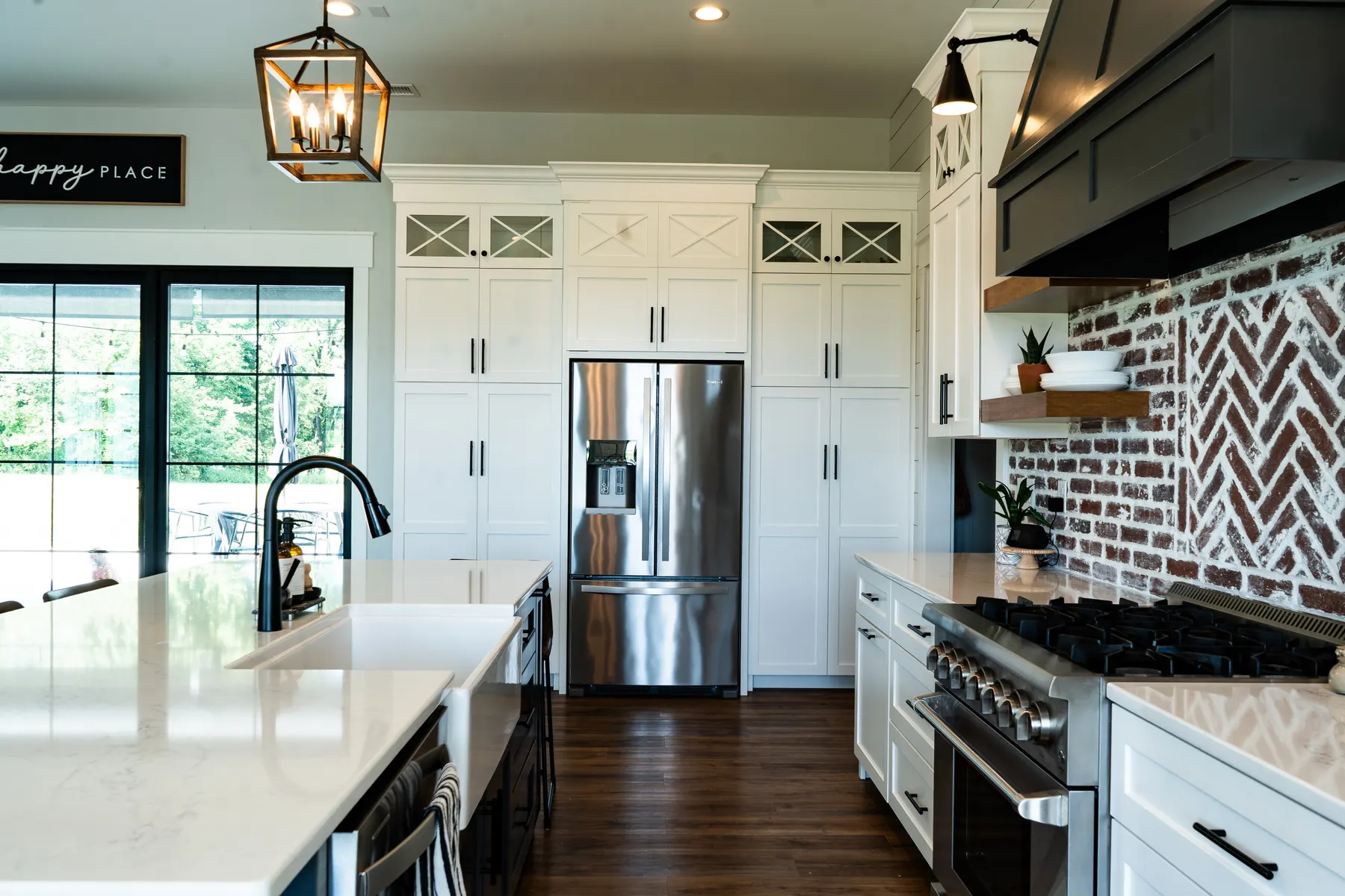 White floor-to-ceiling kitchen cabinets surrounding a stainless refrigerator