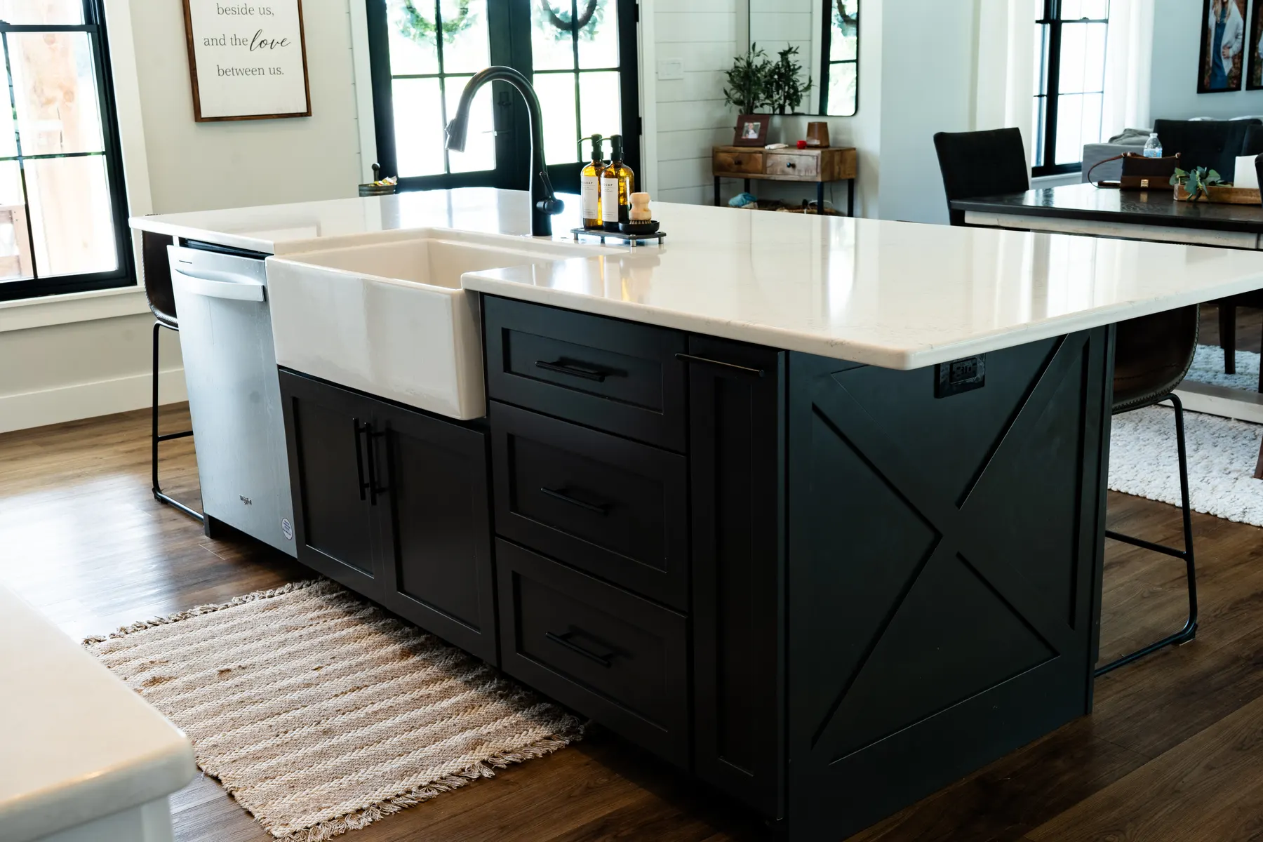 Dark kitchen island with a farmhouse sink, black faucet, and X-brace end panel