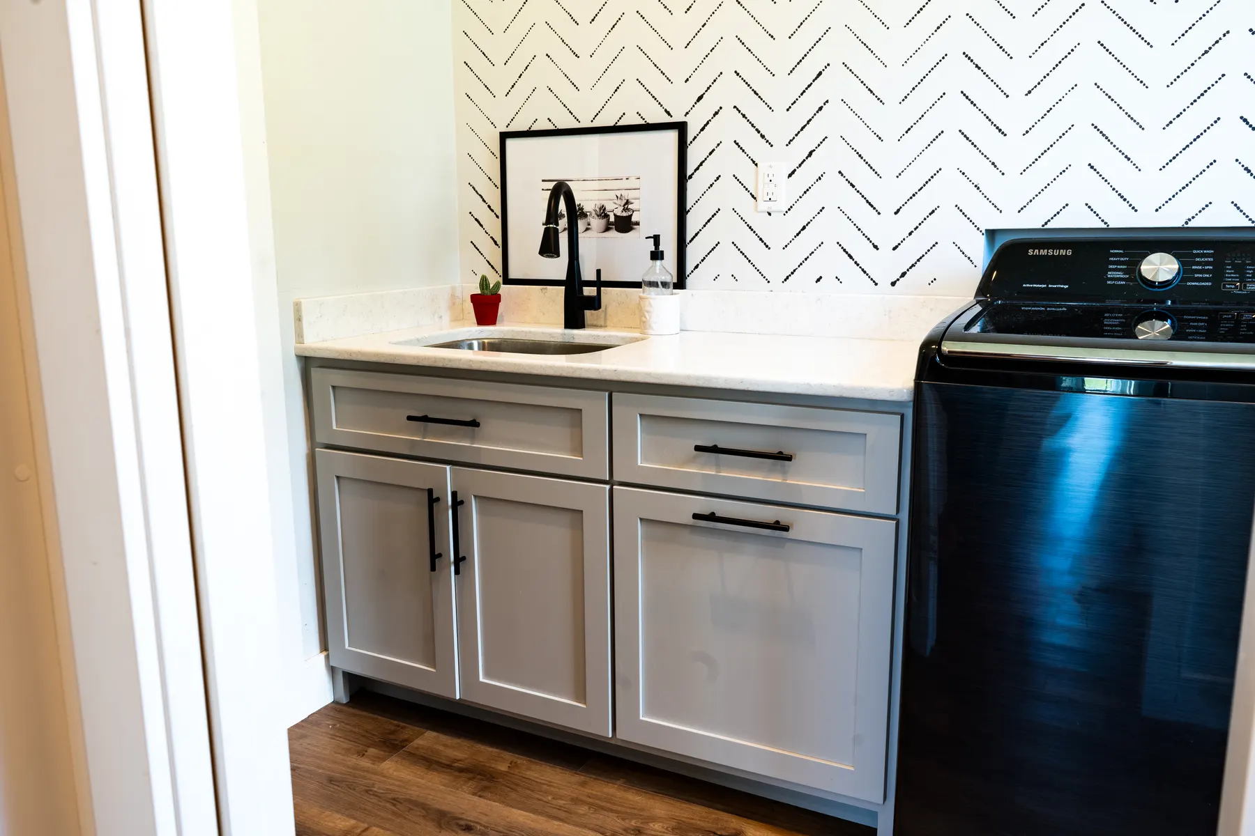 Gray laundry-room cabinets with a white counter and black faucet